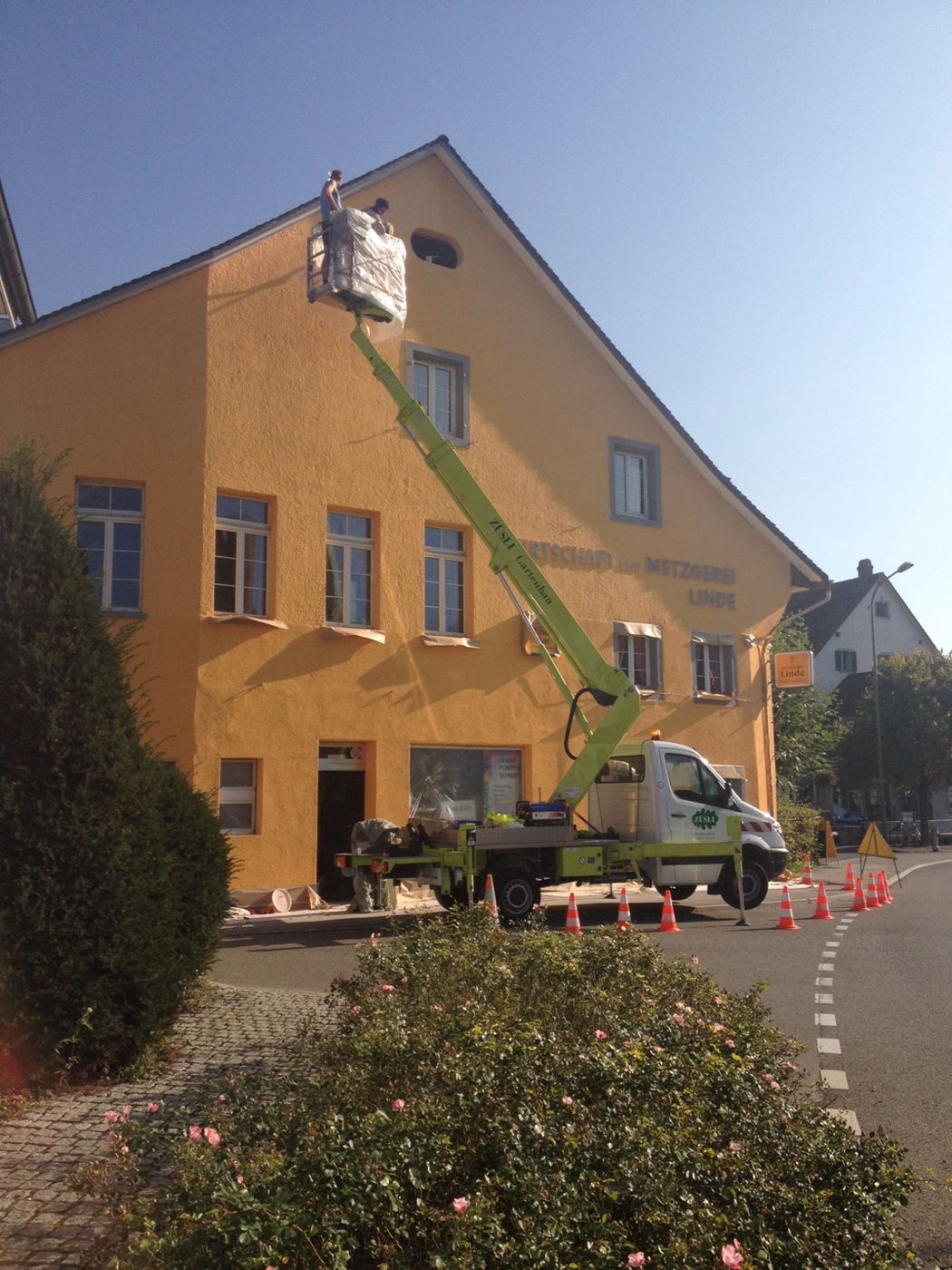 Orangefarbene Hausfassade mit Hebebühne