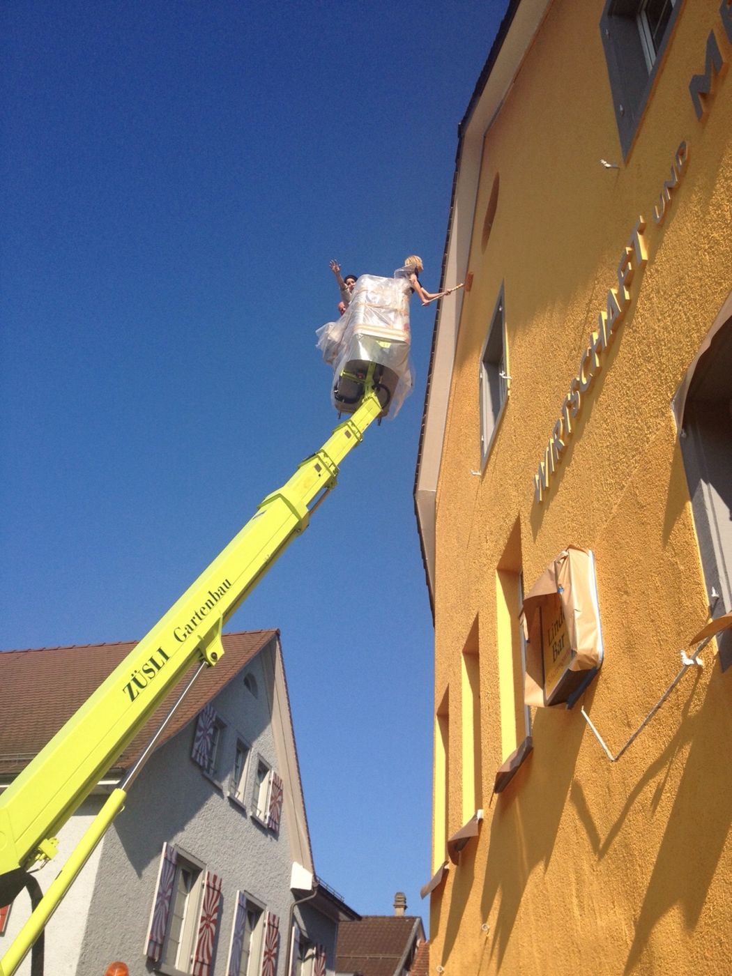 Fassadenarbeiten mit Hebebühne an einem orangefarbenen Haus