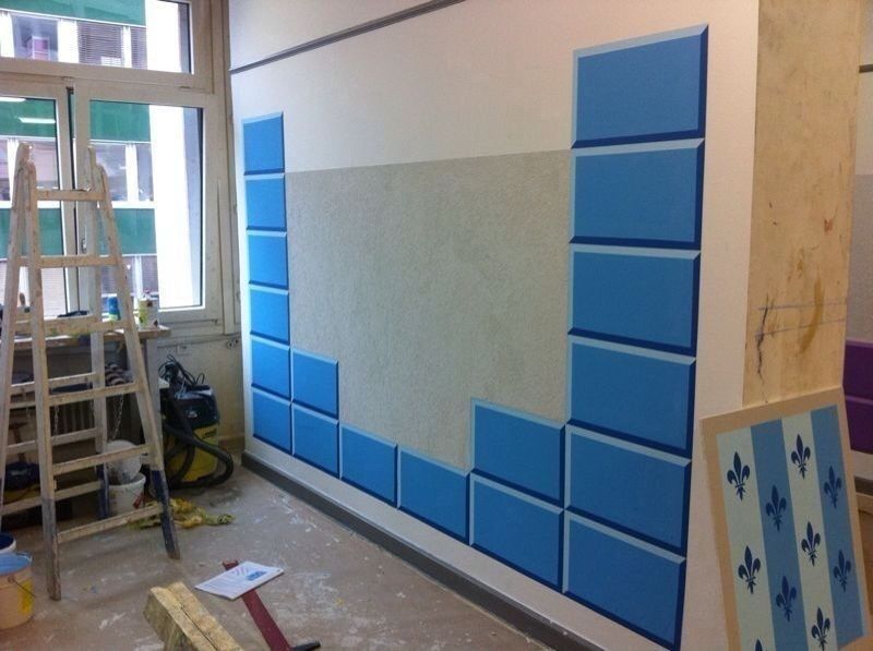Wand mit blauen Farbflächen und einer Leiter im Raum